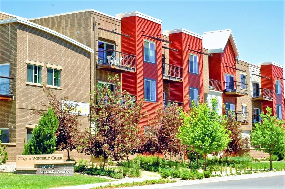 Exterior shot of VWC1, brown brick, orange siding, patios, landscaped with trees and grass